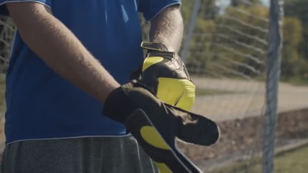 Soccer goalie adjusting goalkeeper gloves outdoors — Stock Video