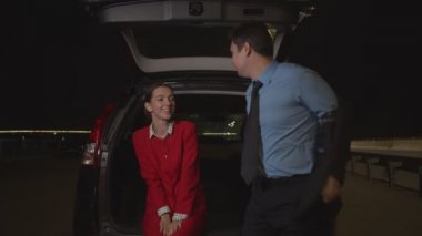 Caring man covering woman with jacket at night