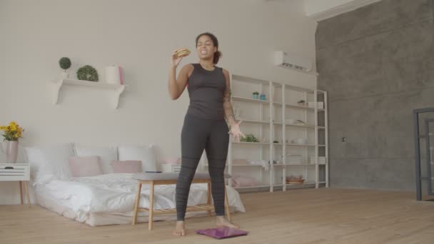 Slimming woman struggles with bait to eat junk food — Stock Video