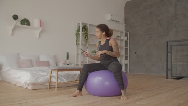 Sportos nő telefonnal élvezi a zenét fitness után — Stock videók