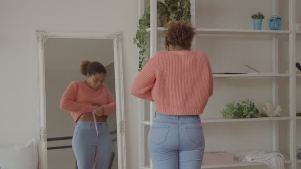 Mulher africana alegre medindo sua cintura em casa — Vídeo de Stock