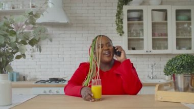 Pozitif Afrikalı kadın evde cep telefonuyla konuşuyor.