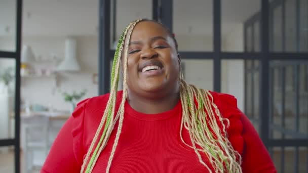 Радостная черная женщина с афрокосичками, смеющаяся в помещении — стоковое видео