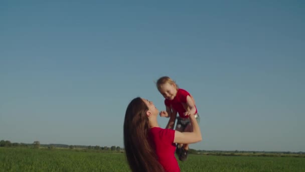 Mutter wirft lachendes Kind im Sommer in die Natur — Stockvideo