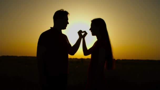 Pareja cogida de la mano en forma de corazón al atardecer — Vídeos de Stock