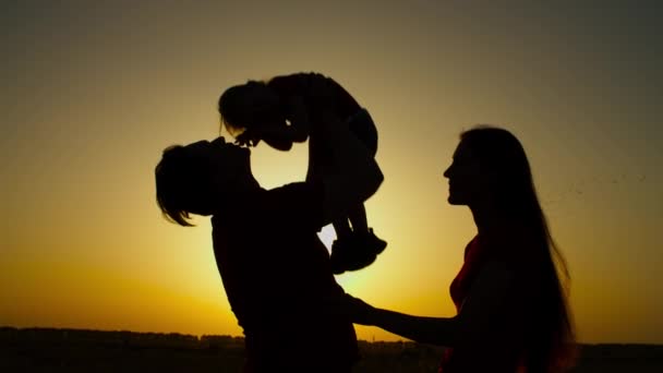Веселая семья с маленькой девочкой, отдыхающей на закате — стоковое видео