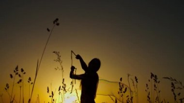 Gün batımında büyük sabun köpüğüyle oynayan kadın.