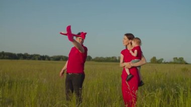 Çocuklu aileler dışarıda oyuncak uçak oynuyorlar.