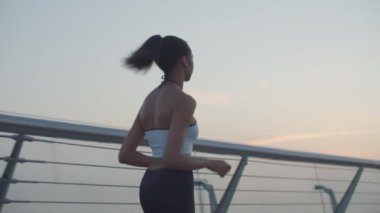 Motive olmuş kadın koşucu sabahın erken saatlerinde koşuyor.