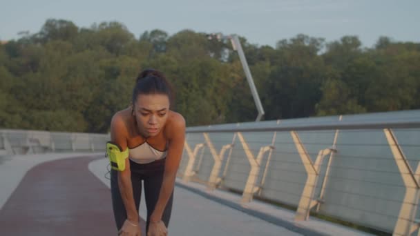 Moe vrouwelijke loper vangt haar adem na jog — Stockvideo