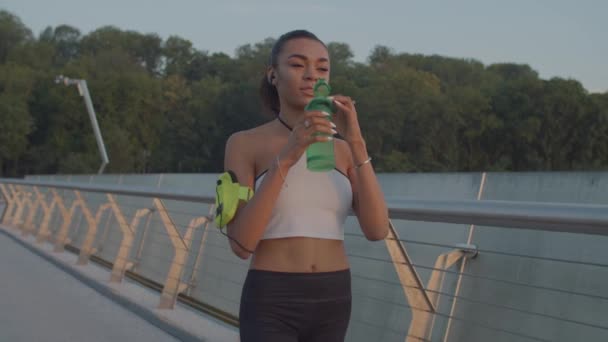 Mujer bebiendo agua durante el entrenamiento correr al amanecer — Vídeo de stock