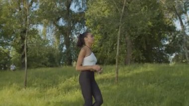 Siyahi kadın koşucu şafak vakti parkta koşuyor.