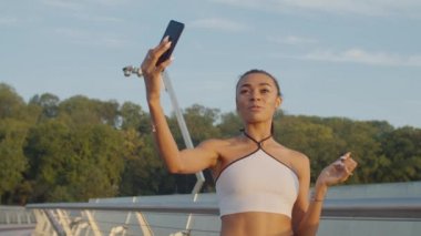 Güneş doğarken cep telefonundan canlı yayın yapan güzel bir kadın.