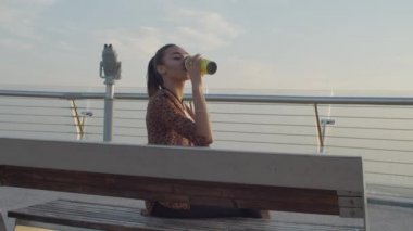 Dinlenmiş kadın gözlem güvertesinde kahve içiyor.