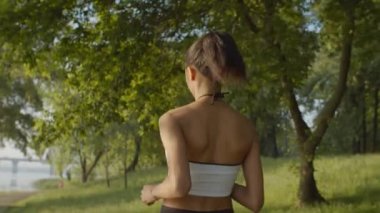Güneş doğarken parkta koşan bayan sporcu.