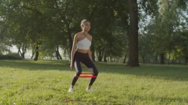 Sportif kadın direniş bandında çömelme yapıyor.