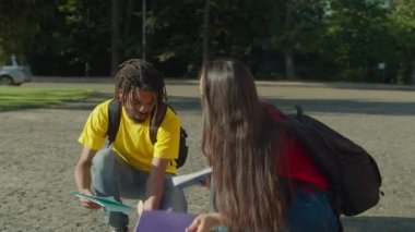 Öğrenci, düşen kağıtları toplamaya yardım ediyor.
