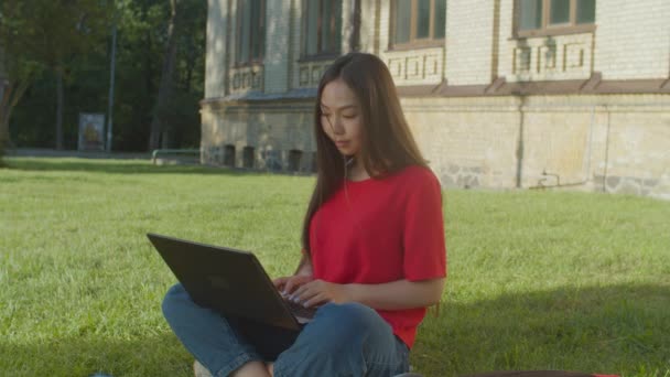 Linda mujer asiática estudiante escribiendo en el portátil al aire libre — Vídeos de Stock