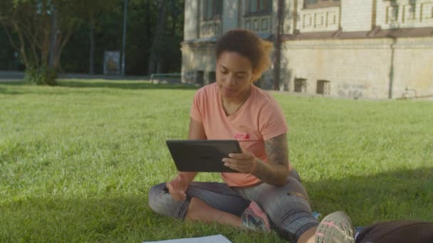 Mujer africana que trabaja con la tableta PC en el césped del parque — Vídeos de Stock