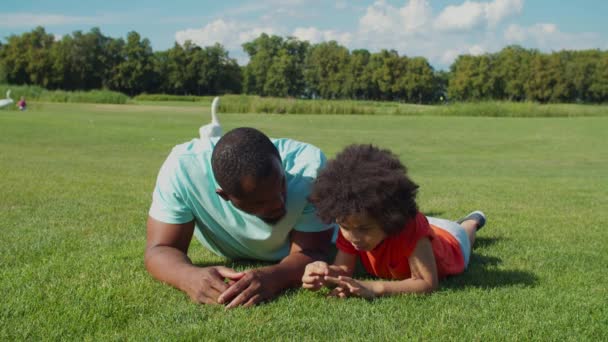 Afrikalı baba ve yakışıklı oğlu park çimlerinde kaynaşıyor. — Stok video