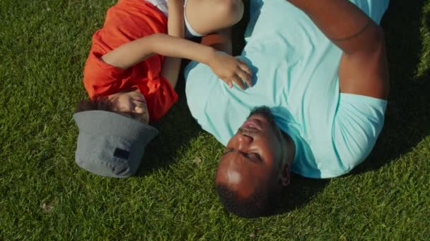 Neşeli bir baba ve yakışıklı bir oğul park çimlerinde yatıyor. — Stok video