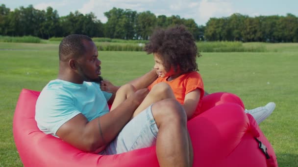 Fröhlicher Vater und Kind relaxen auf der Luftliege im Freien — Stockvideo