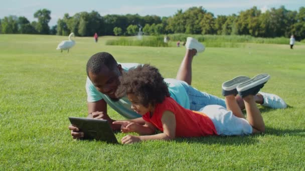 Papà e piccolo figlio che lavorano con tablet pc all'aperto — Video Stock