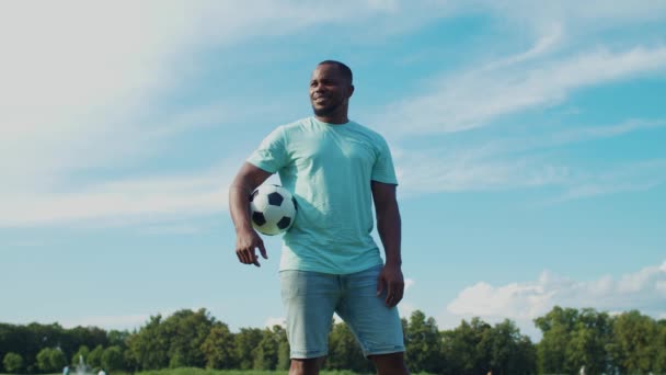 Afryki facet trzyma piłkę nożną w ręku w przyrodzie — Wideo stockowe