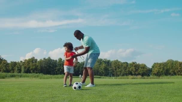 Маленький хлопчик вивчає правила футболу в природі — стокове відео