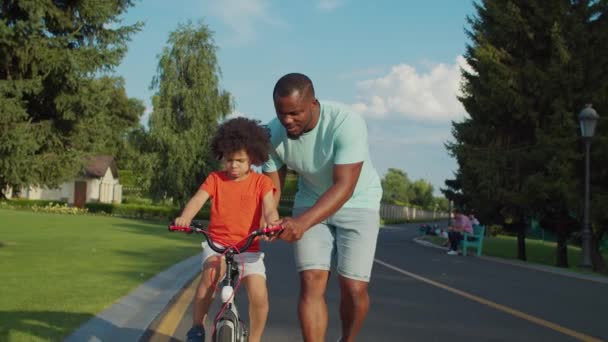 Cuidar do pai segurando menino na bicicleta de equilíbrio — Vídeo de Stock