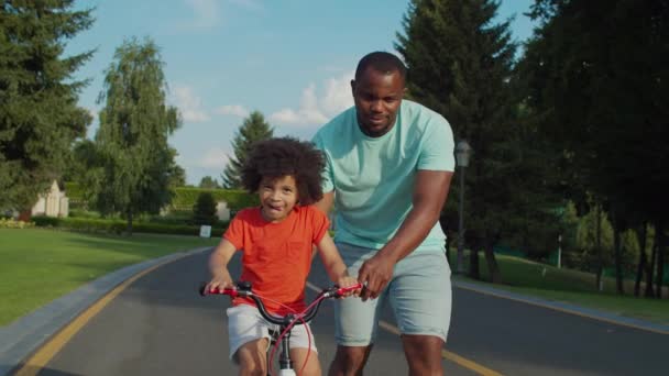 Bonito misto raça menino aprendizagem ciclismo ao ar livre — Vídeo de Stock