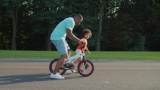 Mischievous far ridning barn cykel i parken — Stockvideo