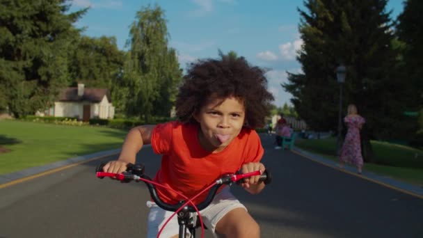 Bonito misto raça menino ter diversão equitação bicicleta no parque — Vídeo de Stock