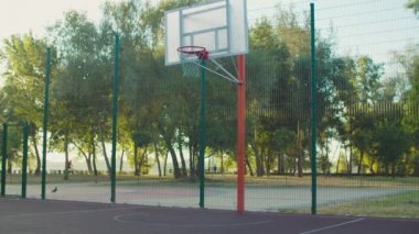 Siyah basketbolcu dışarıda potada asılı duruyor.