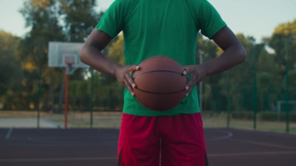 Basketbalspeler houdt bal buiten bij zonsopgang — Stockvideo