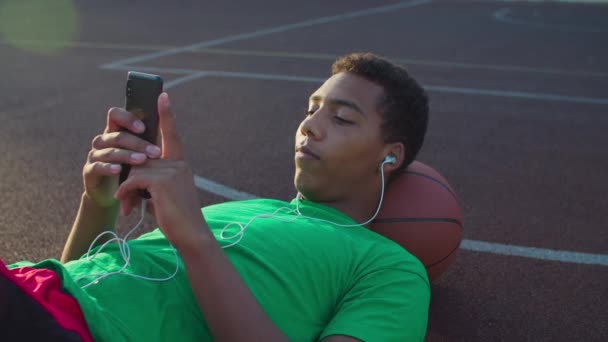 Jogador de basquete alegre ouvir música no telefone — Vídeo de Stock