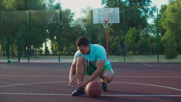 Streetball jugador atando zapato en pista al aire libre — Vídeos de Stock