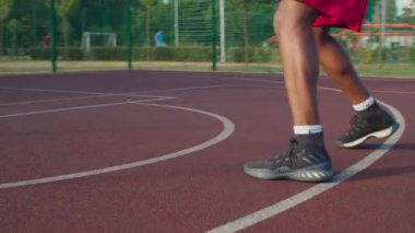 Basketbol sahasında top süren bir sporcu.