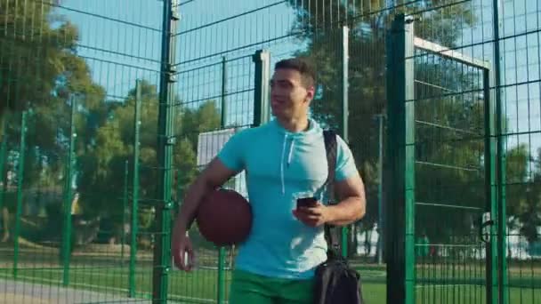 Deportista con teléfono caminando en la cancha antes del juego — Vídeos de Stock