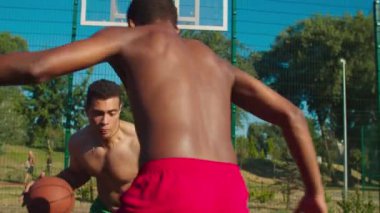 Dışarıda basketbol oynayan iki üstsüz sporcu.