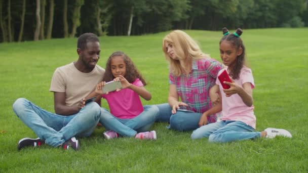 Família diversa com meninas tomando selfie no parque — Vídeo de Stock