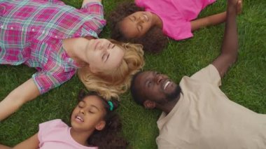 Çeşitli aileler çimenlerde kafa kafaya yatıyor.