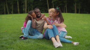 Doğada ebeveynleri kucaklayan iki sevgi dolu kız.