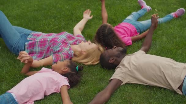 United família de mãos dadas deitado no gramado em círculo — Vídeo de Stock