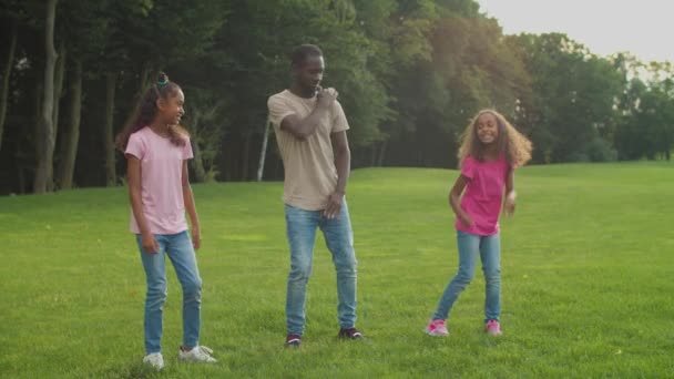 Vreugdevolle vader en dochters dansen op het grasveld — Stockvideo