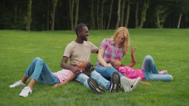 Parkta dinlenen kızları olan çok ırklı bir aile — Stok video