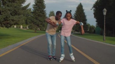 Siyah genç kız parkta paten öğreniyor.