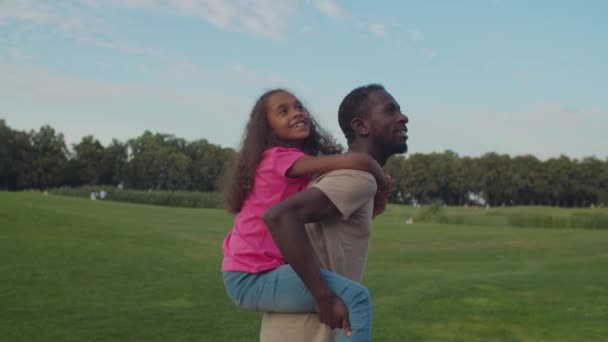 Alegre pai piggybacking animado filha no natureza — Vídeo de Stock