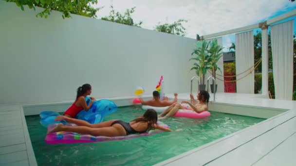 Gelukkige vrienden zwemmen en spelen bal in het zwembad — Stockvideo