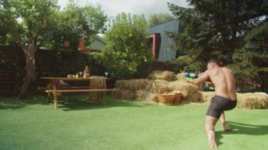 Neşeli adamlar arka bahçede su tabancası savaşı yapıyorlar.